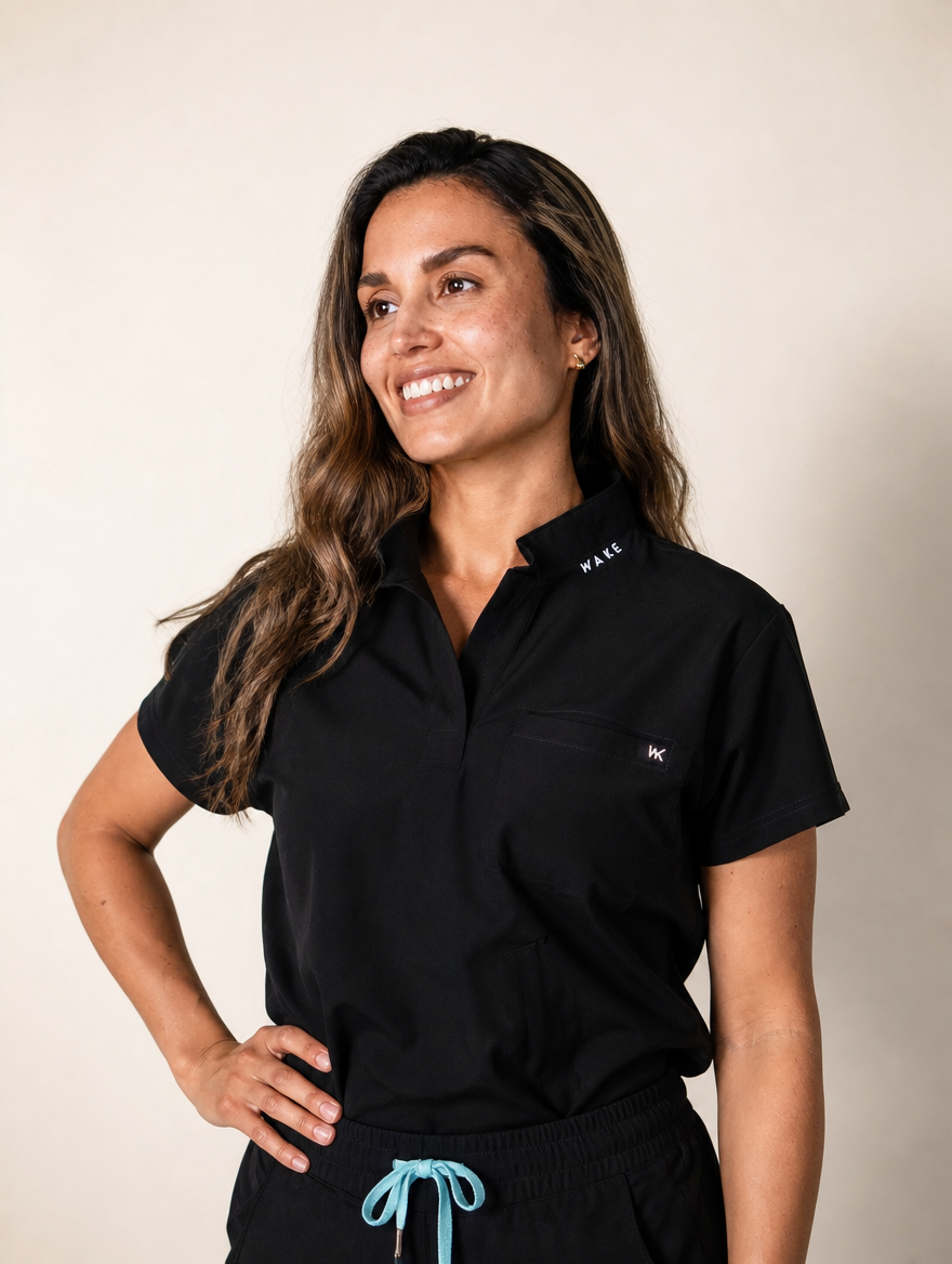Modelo con top negro cuello mao de Wake Health, mano en la cadera y cordón turquesa